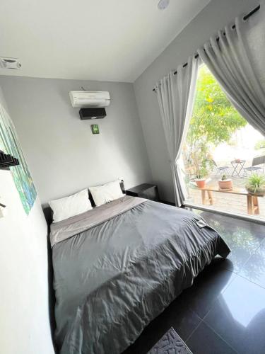a bedroom with a bed and a large window at Evergreen Tree Homestay in Phan Thiet