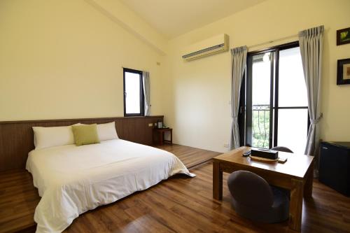 1 dormitorio con cama, mesa y ventana en Landay Homestay en Yilan City