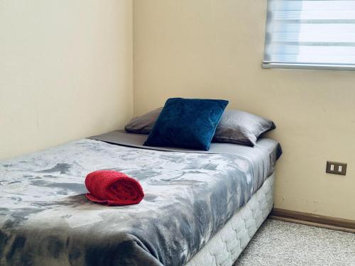 a bed with two pillows and a red hat on it at Dpto Condominio Alto Lomas Del Carmen in Temuco