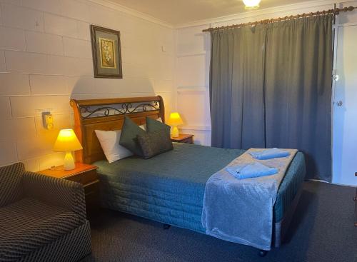 um quarto com uma cama, uma cadeira e uma janela em Warrego Motel em Charleville