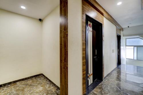 a hallway with a black door and a tile floor at OYO Hotel Signature in Ahmedabad