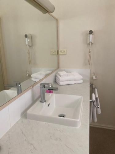 a bathroom with a sink and a mirror at Deniliquin Country Club Motor Inn in Deniliquin