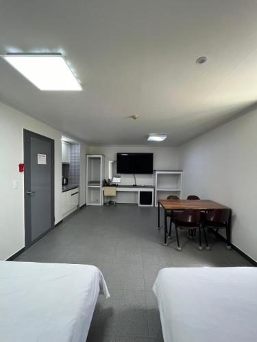 a room with two beds and a table and a television at Motel Choo Eok in Sokcho