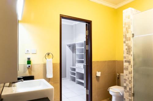 baño con lavabo, aseo y paredes amarillas en LA CASA BORNEO, en Bentakan Kecil