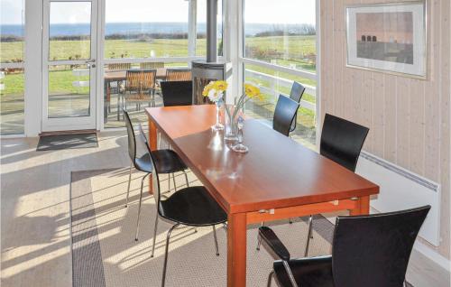a wooden table and chairs in a room with windows at Holiday Home Bellevue Iii in Skovby