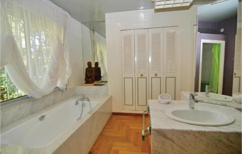 ein weißes Badezimmer mit einer Badewanne und einem Waschbecken in der Unterkunft Lovely Home In Aubais With Wifi in Aubais