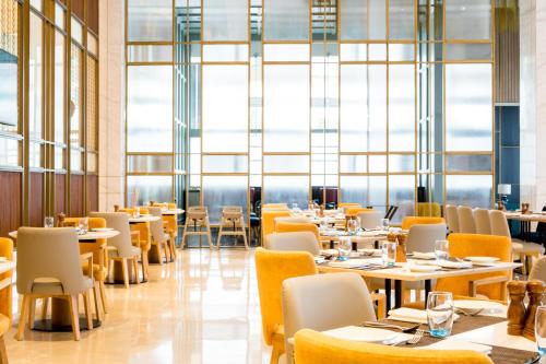 a restaurant with tables and chairs and large windows at Holiday Inn Lucknow Airport by IHG in Lucknow