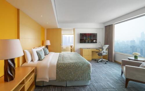 a hotel room with a bed and a desk and a window at Marco Polo Wuhan in Wuhan