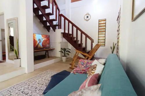 a living room with a blue couch and stairs at CamiStays Homestay in Camiguin, Best for Groups or Family in Mambajao