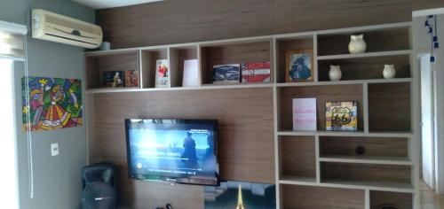 a living room with a flat screen tv on a wooden wall at Apartamento na Serra Gaúcha in Caxias do Sul