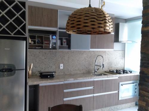 a kitchen with a sink and a large pendant light at Apartamento na Serra Gaúcha in Caxias do Sul
