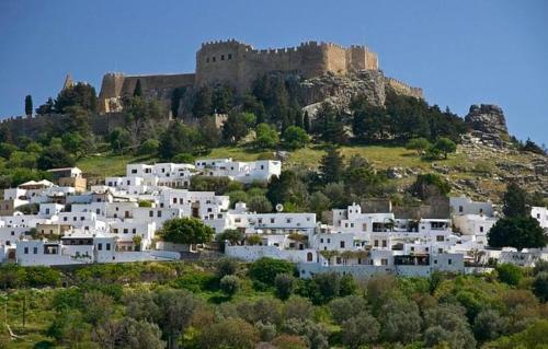 un grupo de casas blancas en una colina con un castillo en Paradise Apartment, Lardos Village, en Lardos