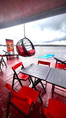 a boat with chairs and a table and a swing at Casa flutuante - Manaus Amazonas in Manaus