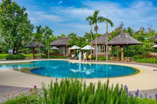 una piscina en un complejo con gente caminando alrededor en Tongna Cottage Natural Resort en Chiang Mai