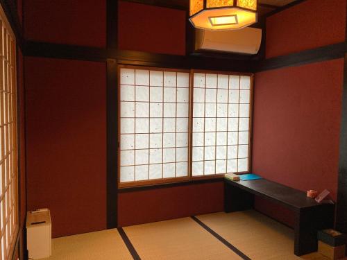 a room with two windows and a bench in front of it at ゲストハウスみんちゅう in Sukumo