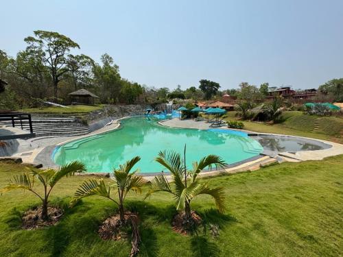 a large swimming pool with palm trees in a field at The Dandelion - Colonels Jungle Resort in Khānāpur