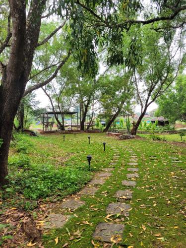 a stone path in a park with a tree at The Dandelion - Colonels Jungle Resort in Khānāpur