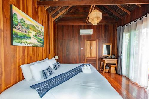 a bedroom with a large white bed with wooden walls at Tongna Cottage Natural Resort in Chiang Mai