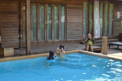 three children are sitting in a swimming pool at Tongna Cottage Natural Resort in Chiang Mai