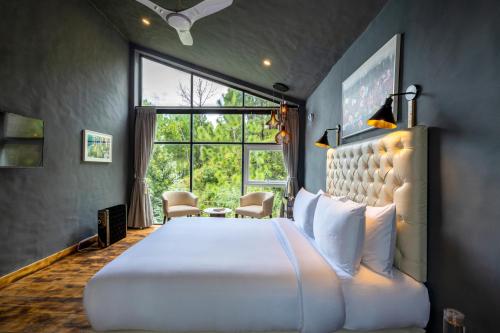 a bedroom with a large white bed and a window at amã Stays & Trails Serendipity, Ranikhet in Rānīkhet