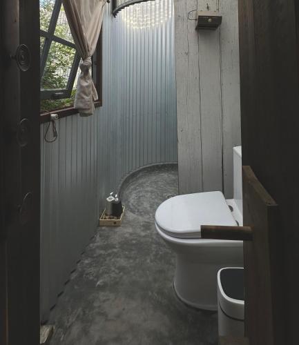 a bathroom with a toilet and a window at Dreamer Cabin Tre house Dalat in Da Thien