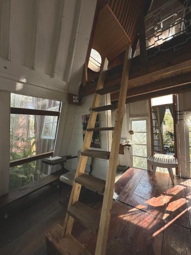 a wooden staircase in a tiny house with windows at Dreamer Cabin Tre house Dalat in Da Thien