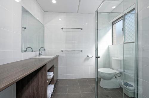 a bathroom with a toilet and a glass shower at Chalet Motor Inn in Bundaberg