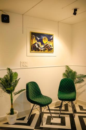 two green chairs in a room with a painting at Agrah Stay - Kasa Lusso Stay in Faridabad