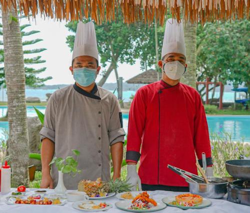 two chefs standing in front of a table with plates of food at Mutiara Carita Cottages in Carita