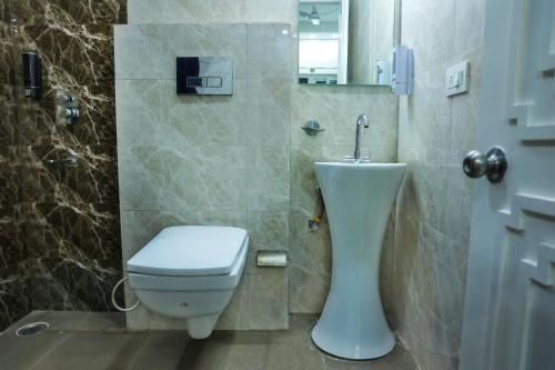 La salle de bains est pourvue de toilettes et d'un lavabo. dans l'établissement Agrah Stay - Kasa Lusso Stay, à Faridabad