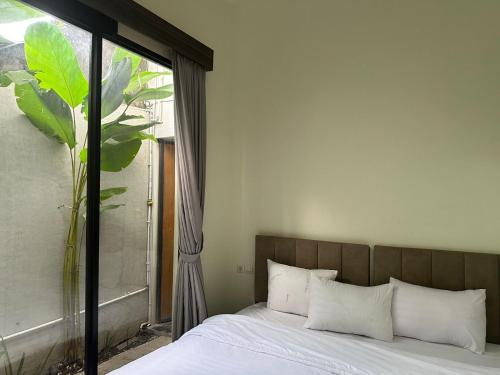 Una cama con almohadas blancas y una ventana en una habitación. en Nofrah House Syariah Mitra RedDoorz en Colomadu