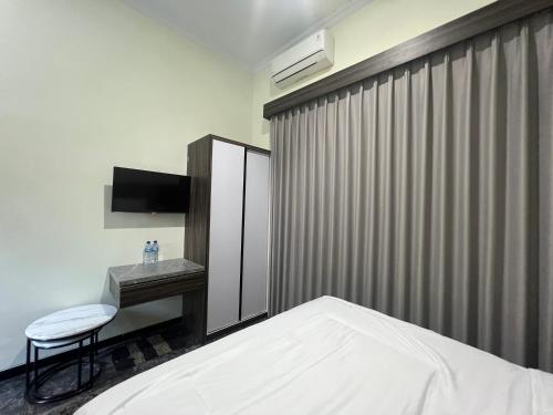 a bedroom with a bed and a table and a chair at Nofrah House Syariah Mitra RedDoorz in Tjolomadu