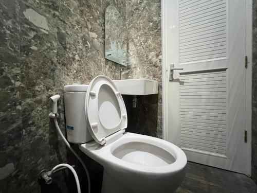 a bathroom with a toilet with the lid up at Nofrah House Syariah Mitra RedDoorz in Tjolomadu