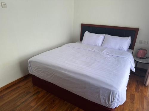 a bedroom with a large bed with white sheets and pillows at Nofrah House Syariah Mitra RedDoorz in Tjolomadu
