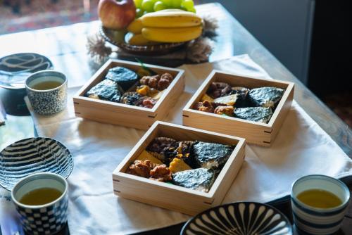 three wooden boxes of food on a table with cups of tea at Shinagawa-ku - House / Vacation STAY 12126 in Tokyo