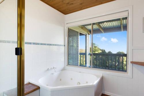 Windsong at Ravensbourne Escape 1 Bedroom في Ravensbourne: حمام أبيض مع حوض استحمام ونافذة