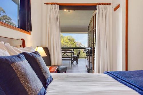 um quarto com uma cama e vista para um alpendre em Cedar Lodge - Cosy Mountain Retreat 1 Bedroom em Ravensbourne