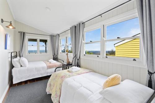 una camera con due letti e una casa gialla di The Quince Cottage - 3 Bedrooms a Ravensbourne