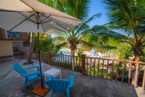 a patio with chairs and an umbrella and palm trees at Hotel Casa Rush in Puerto Ángel
