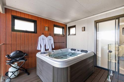 uma banheira de hidromassagem num quarto com paredes de madeira em Affinity Luxury Studio with Spa and Amazing Views em Ravensbourne