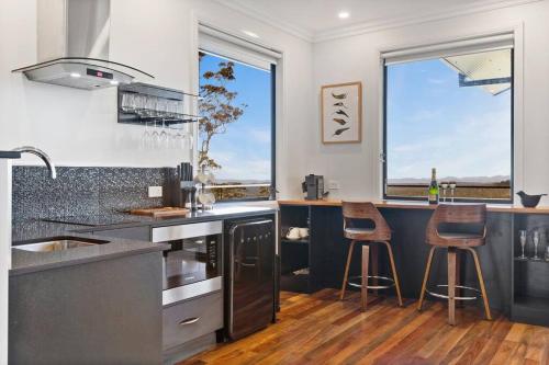 a kitchen with a counter with two bar stools at Affinity Luxury Studio with Spa and Amazing Views in Ravensbourne