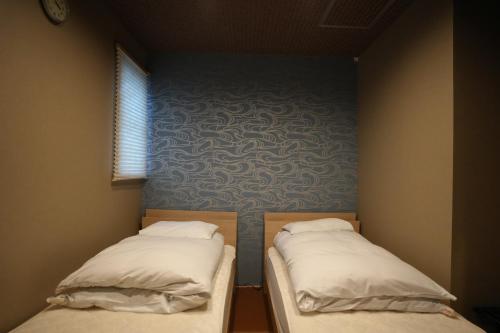 two beds in a small room with a blue wall at Guest House Takiyoshi in Hongu