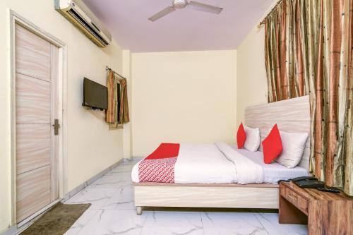 Schlafzimmer mit einem Bett mit roten Kissen und einem TV in der Unterkunft Vishwakarma Palace in Neu-Delhi