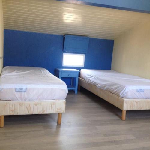 Cette chambre comprend 2 lits et un mur bleu. dans l'établissement Charmante maison à 500m de la plage Rémigeasse, à Dolus-d'Oléron