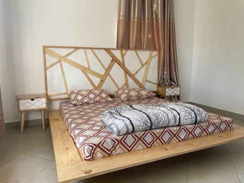 a bed with a wooden frame and pillows on it at The Lavish Condo -Wandegeya in Kampala