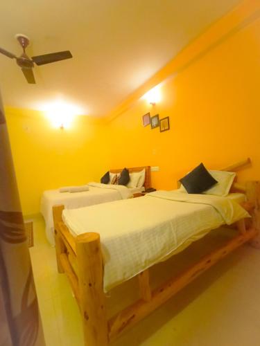 two beds in a room with yellow walls at JMT Eco-Binsar by StayApart in Panuānaula