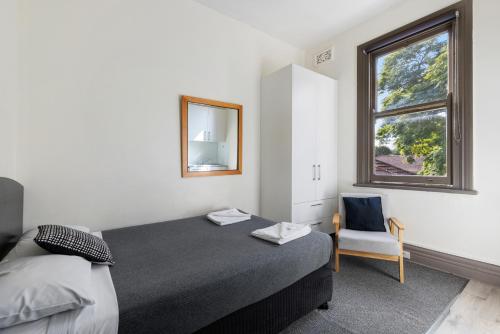 1 dormitorio con cama, ventana y silla en Falcon Lodge, en Sídney