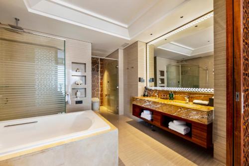 La salle de bains est pourvue d'une baignoire et d'un grand miroir. dans l'établissement Fondney Hotel Shanghai Hongqiao, à Shanghai