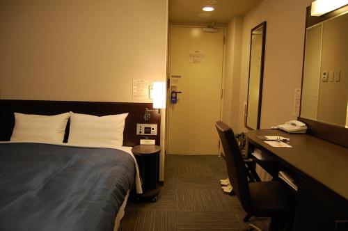 a hotel room with a bed and a desk and a mirror at Hotel Route-Inn Nabari in Nabari