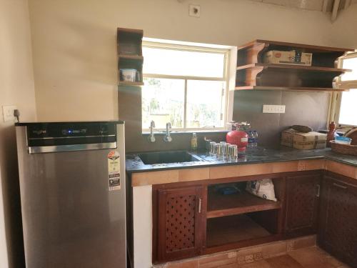 a kitchen with a stainless steel refrigerator and a sink at Cocoon Earth Home - Pool Villa Kovalam in Kovalam